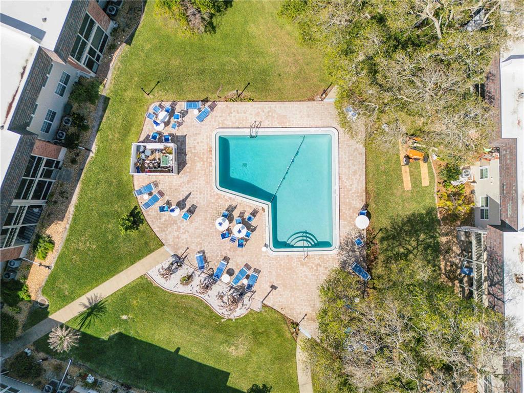 An aerial view shows an L-shaped swimming pool surrounded by a paved deck and lawn — 3800 SAXON DRIVE UNIT A7, NEW SMYRNA BEACH, FL