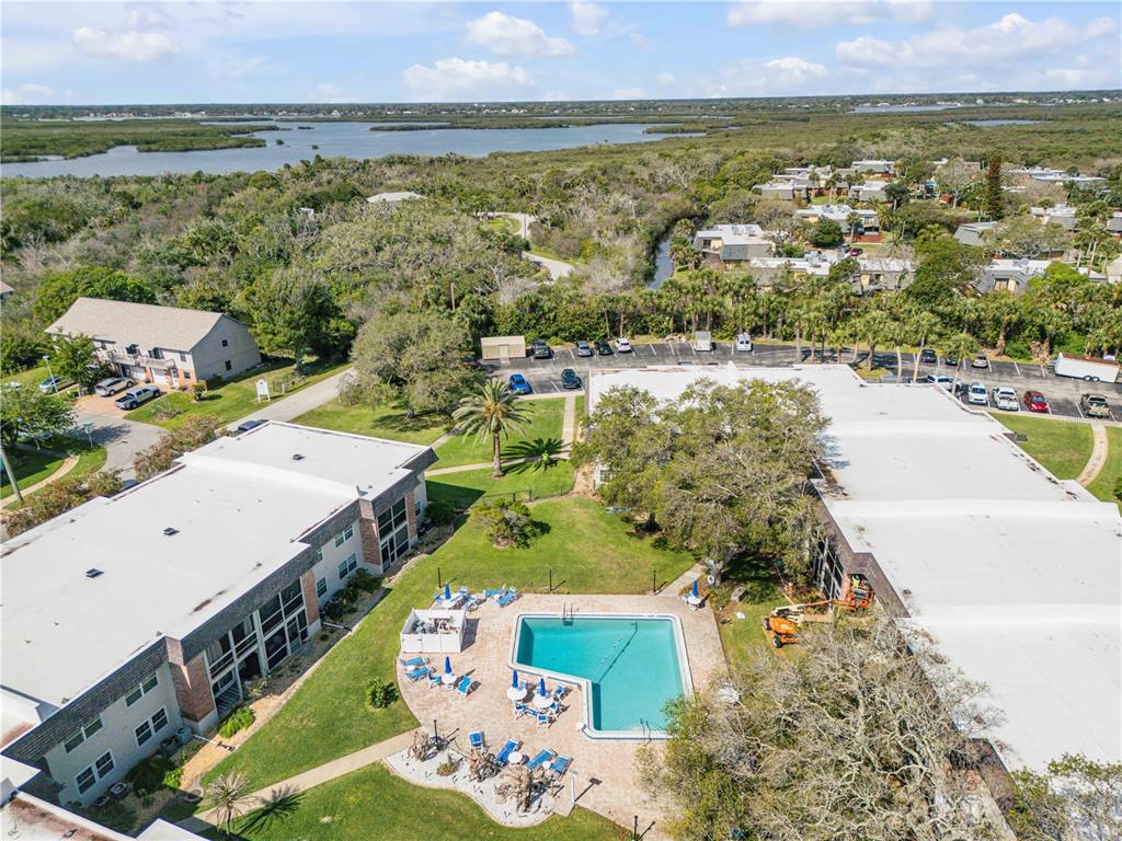 An aerial view shows two apartment buildings with a central swimming pool and parking lot — 3800 SAXON DRIVE UNIT A7, NEW SMYRNA BEACH, FL