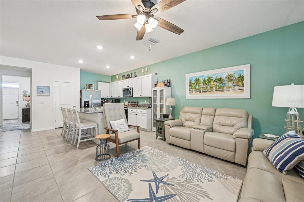 An open-concept living room and kitchen featuring tile floors, a teal accent wall, and furniture — 16646 MAUDE DRIVE, WIMAUMA, FL