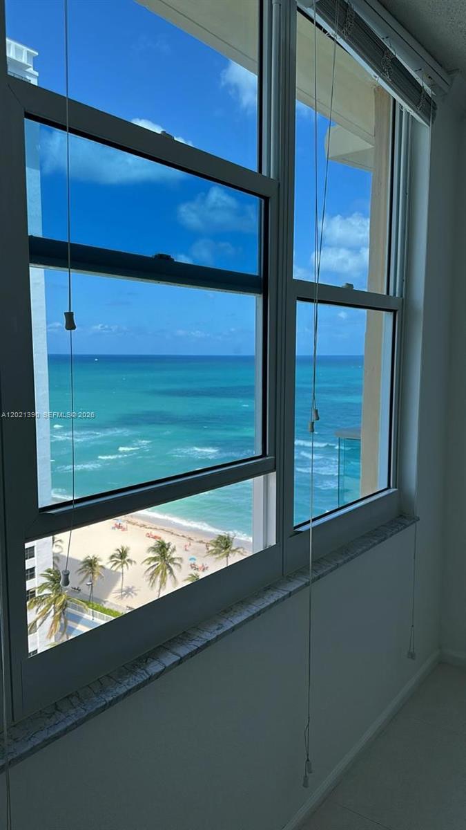 A view of the ocean and beach through a large window in a room — 2501 S Ocean Dr # 1603, Hollywood FL 33019, HOLLYWOOD, FL