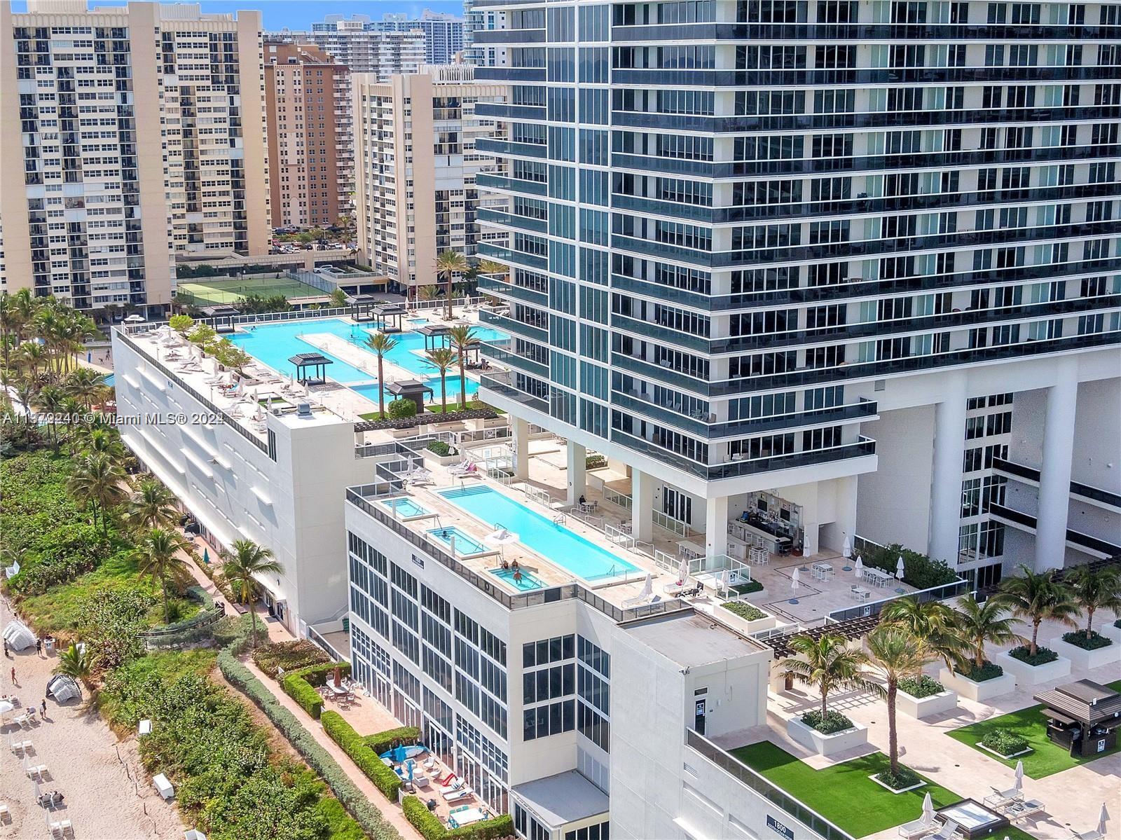 An aerial view shows a high-rise building with multiple swimming pools and a beachside location — 1830 S Ocean Dr # 2010, Hallandale Beach FL 33009, HALLANDALE BEACH, FL