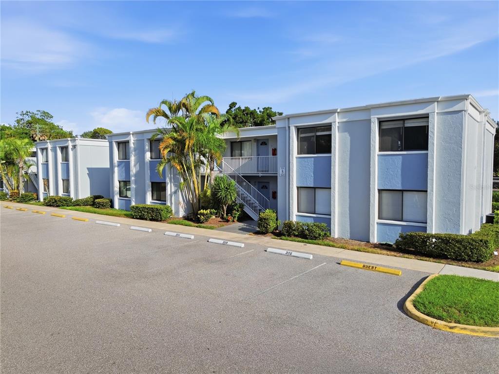 A two-story apartment building with blue and white exterior walls sits behind a parking lot — 5310 26TH STREET W UNIT 304, BRADENTON, FL