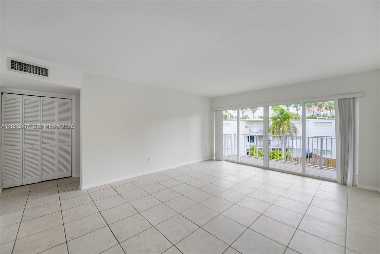 An empty living room features white walls, tile flooring, a sliding glass door, and a closet — 7737 SW 88th St # C312, Miami FL 33156, MIAMI, FL