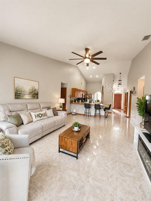 A living room with light tile floors, a sectional sofa, and an open kitchen — 1927 GAMBOGE DRIVE, ORLANDO, FL