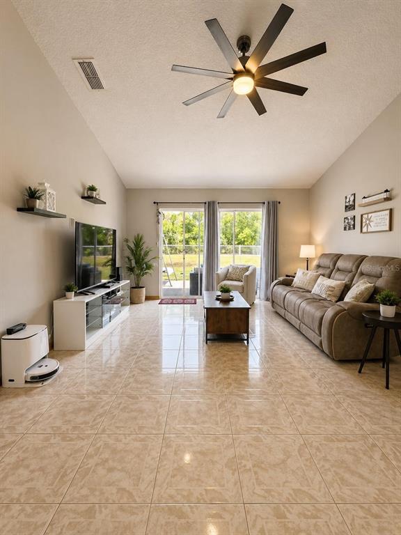 A living room features tile flooring, a vaulted ceiling with a ceiling fan, and sliding doors — 1927 GAMBOGE DRIVE, ORLANDO, FL
