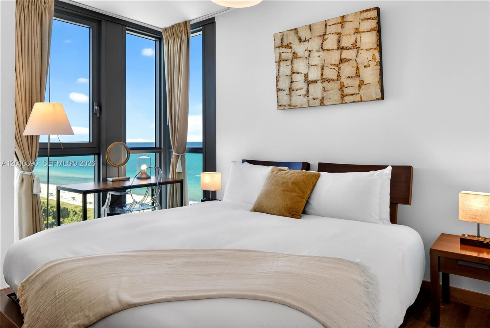 A bedroom features a bed, a desk by a window, and an ocean view — 101 20th St # 2601, Miami Beach FL 33139, MIAMI BEACH, FL