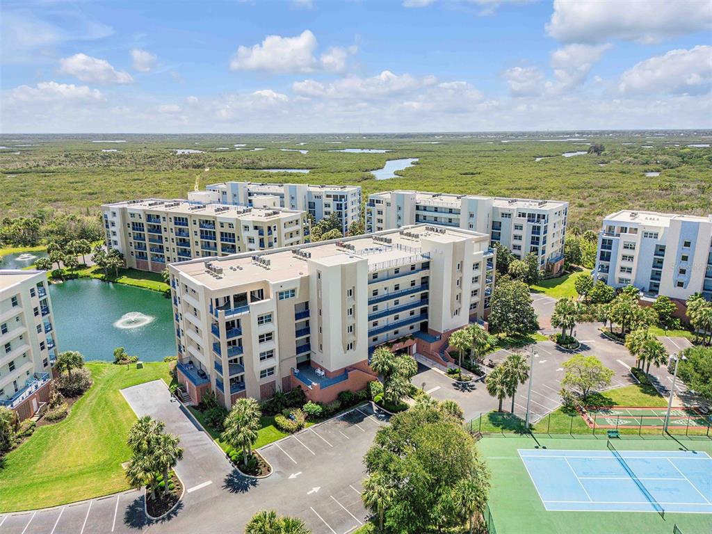 An aerial view shows multi-story apartment buildings, a pond with a fountain, and a tennis court — 5300 S ATLANTIC AVENUE UNIT 8-206, NEW SMYRNA BEACH, FL