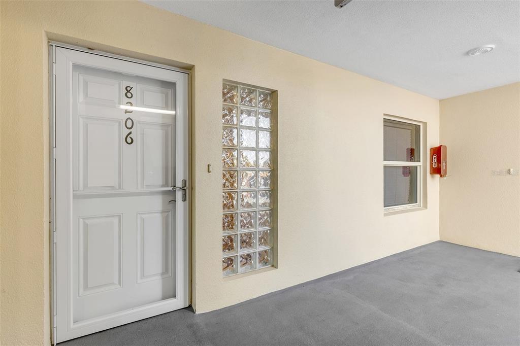 A white door with a glass block window and a fire extinguisher on the wall — 5300 S ATLANTIC AVENUE UNIT 8-206, NEW SMYRNA BEACH, FL