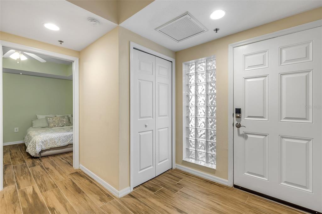 An entryway features wood-look tile flooring, a glass block window, and a white closet door — 5300 S ATLANTIC AVENUE UNIT 8-206, NEW SMYRNA BEACH, FL