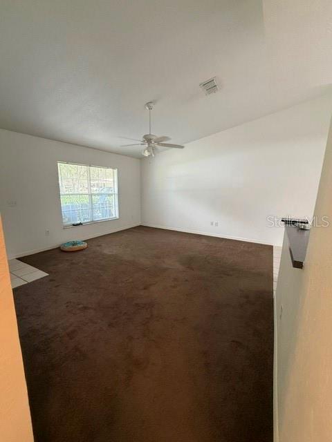 A living room features brown carpeting, a ceiling fan, and a window with white trim — 3100 SW 94TH STREET UNIT 2, OCALA, FL