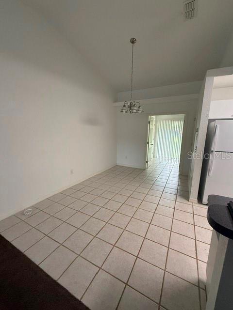 A dining area with white walls, a vaulted ceiling, and light-colored square floor tiles — 3100 SW 94TH STREET UNIT 2, OCALA, FL