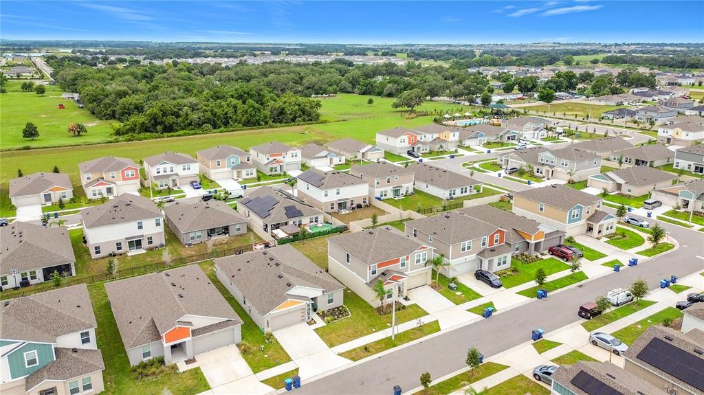 An aerial view shows a suburban neighborhood with single-family homes, paved streets, and green lawns — 1414 SEA GLASS ROAD, HAINES CITY, FL