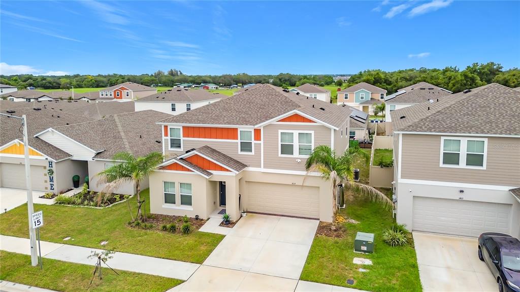 An aerial view shows a two-story suburban house with a garage and tan siding — 1414 SEA GLASS ROAD, HAINES CITY, FL