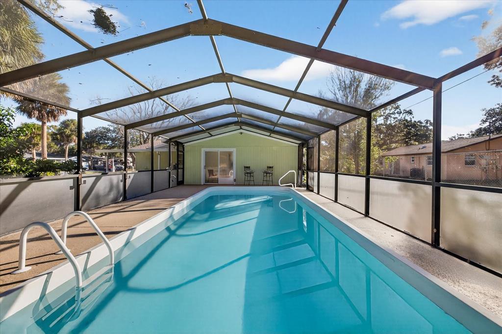 A rectangular swimming pool is enclosed by a screened-in lanai with a concrete deck — 4928 AMHERST COURT, NEW PORT RICHEY, FL