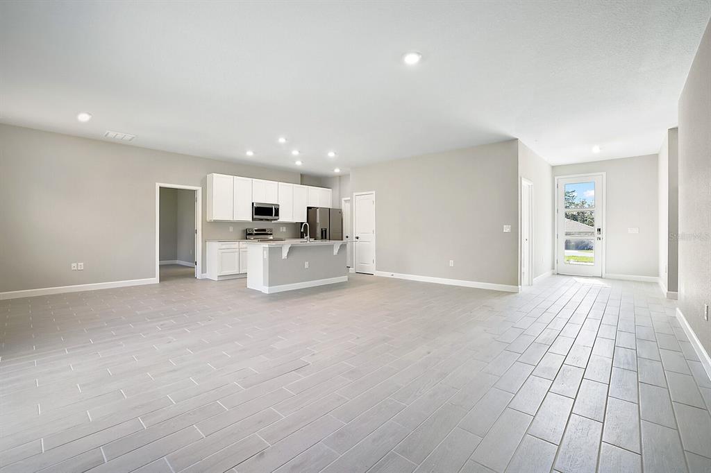 An open-concept kitchen and living area features light gray tile flooring and white cabinetry — 13420 SW 29TH CIRCLE, OCALA, FL