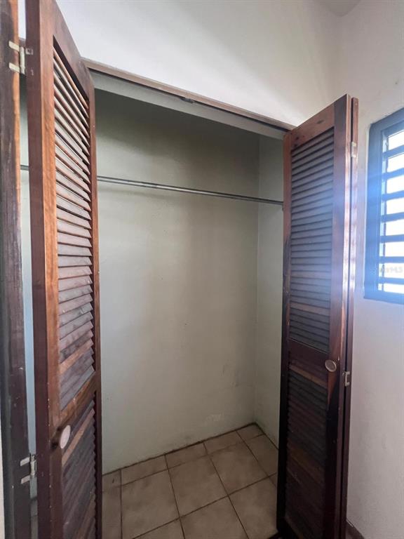 A closet with wooden louvered doors, a metal hanging rod, and tiled flooring — 708 Ave  Fernandez Juncos MIRAMAR, SAN JUAN, PR