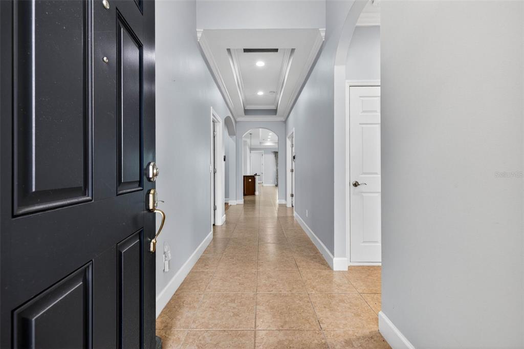 A view from an open front door looking down a tiled hallway with tray ceilings — 712 CHIPPER DRIVE, SUN CITY CENTER, FL