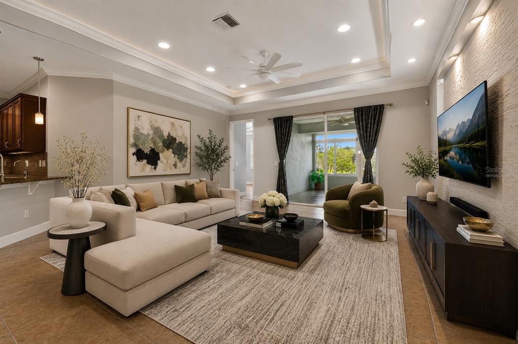 A living room features a sectional sofa, a coffee table, and a wall-mounted television — 712 CHIPPER DRIVE, SUN CITY CENTER, FL