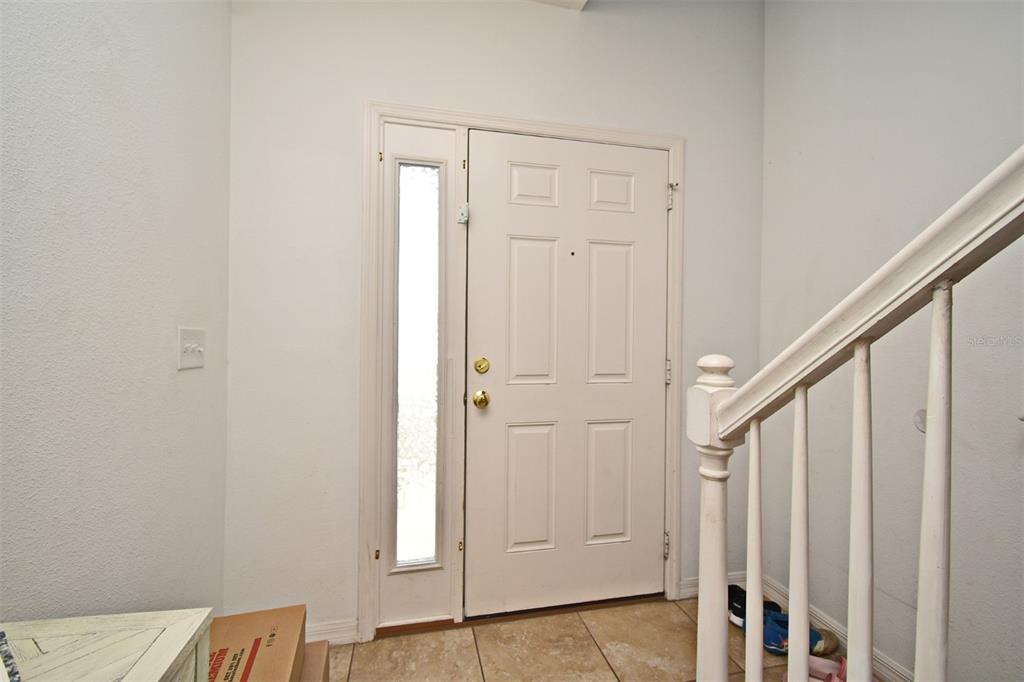 An entryway features a white front door with a sidelight, tile flooring, and a staircase — 1524 DOWNY BIRCH LANE, LONGWOOD, FL
