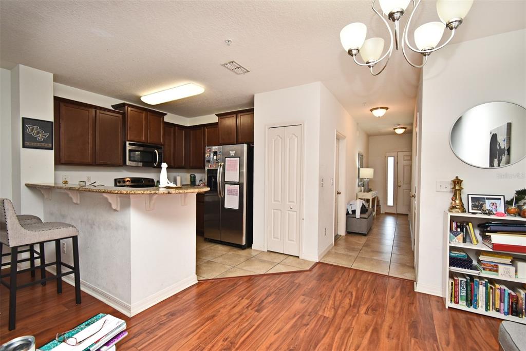 A kitchen with dark wood cabinets and a breakfast bar overlooks a living area — 1524 DOWNY BIRCH LANE, LONGWOOD, FL