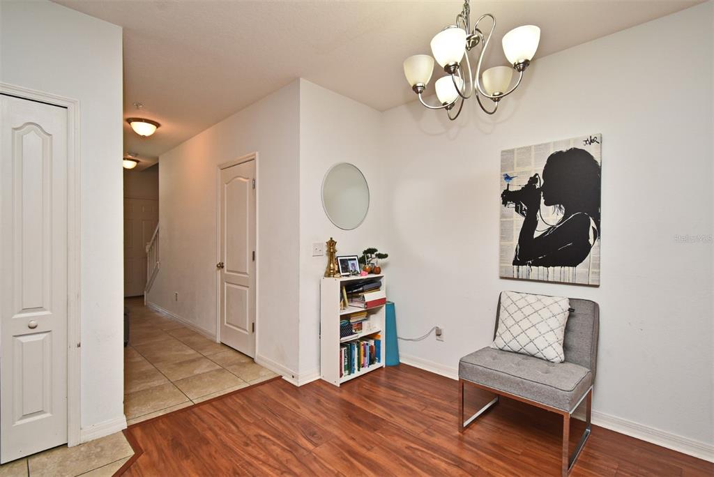 A foyer features wood-look flooring, a gray accent chair, a bookshelf, and a chandelier — 1524 DOWNY BIRCH LANE, LONGWOOD, FL