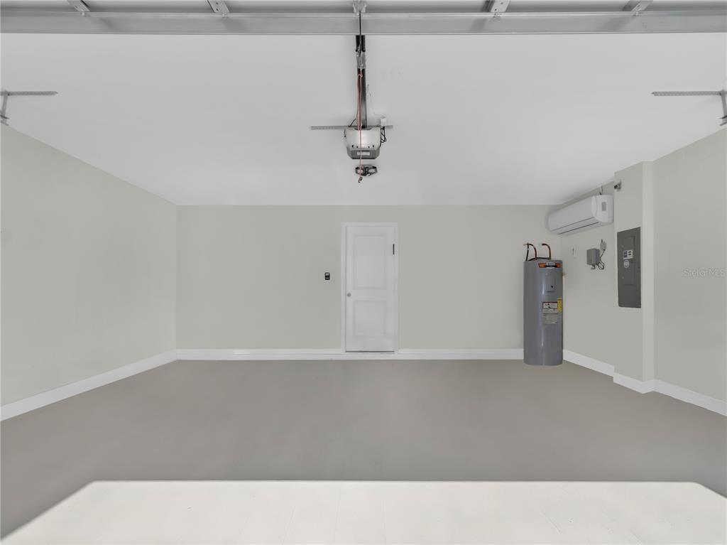An empty garage with light gray walls, a concrete floor, a water heater, and HVAC unit — 16767 SUNBURST LAKE STREET, WIMAUMA, FL