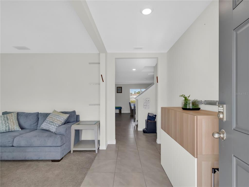 An entryway leads to a living area with a blue sofa and tiled flooring — 16767 SUNBURST LAKE STREET, WIMAUMA, FL