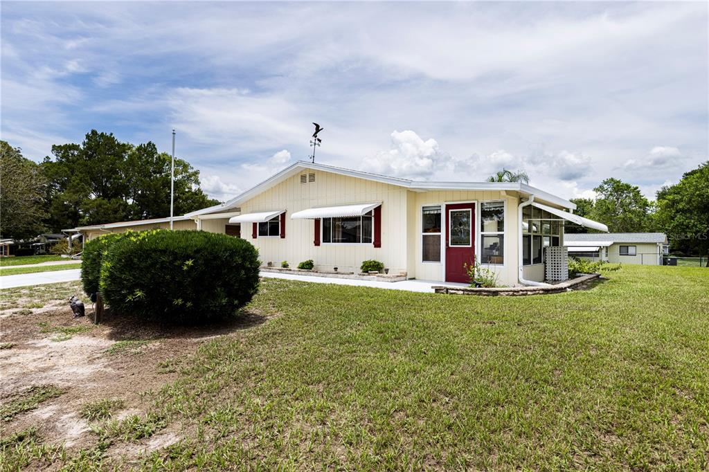 A light yellow single-story house with a red front door and a large front lawn — 9035 SW 102ND PLACE, OCALA, FL
