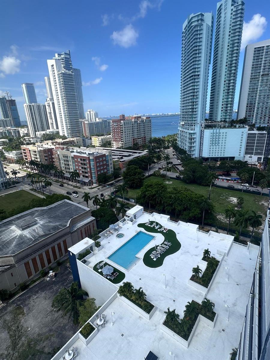 An elevated view of a building rooftop pool deck overlooking a city skyline and bay — 275 NE 18th St # 1902, Miami FL 33132, MIAMI, FL