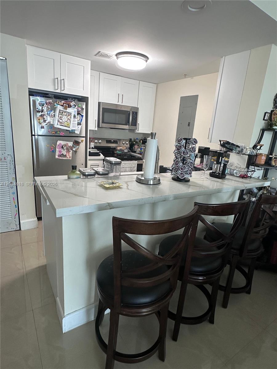 A kitchen features white cabinets, stainless steel appliances, and a quartz-topped island with bar stools — 275 NE 18th St # 1902, Miami FL 33132, MIAMI, FL