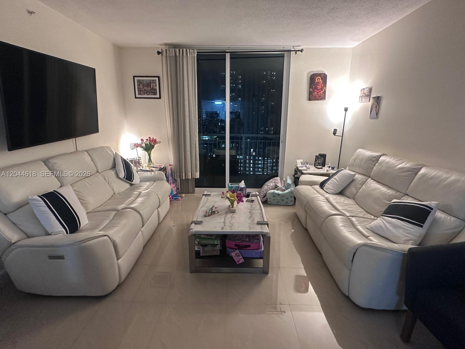 A living room features two white leather sofas, a marble coffee table, and a balcony — 275 NE 18th St # 1902, Miami FL 33132, MIAMI, FL