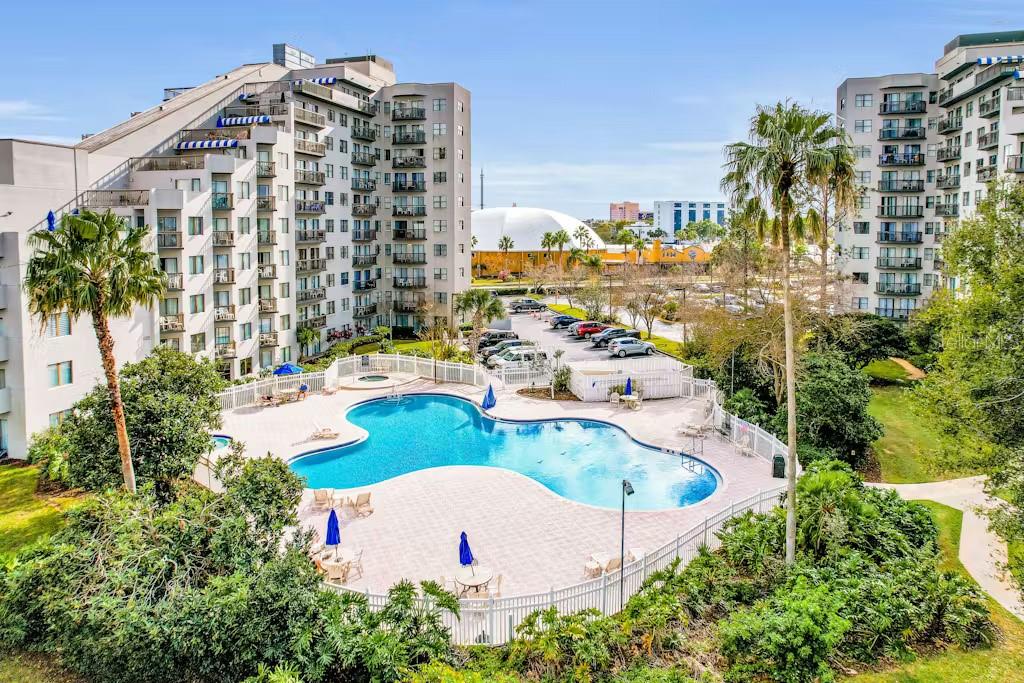 An elevated view of a swimming pool surrounded by apartment buildings and a parking lot — 6165 CARRIER DRIVE UNIT 3604, ORLANDO, FL