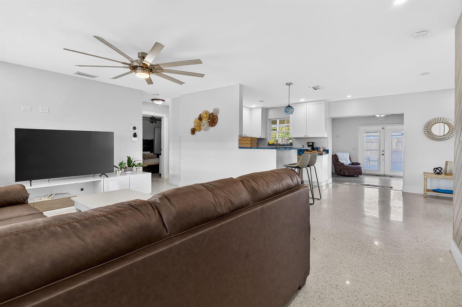A living room with a brown sofa, large television, and open kitchen with bar seating — 1123 SE 2nd Avenue, Deerfield Beach FL 33441, DEERFIELD BEACH, FL