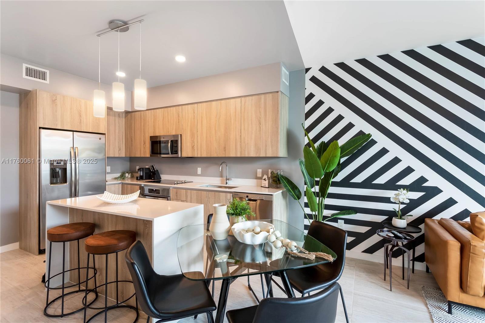 A modern kitchen and dining area feature light wood cabinets, white countertops, and striped wallpaper — 3900 Biscayne Blvd # 314, Miami FL 33137, MIAMI, FL