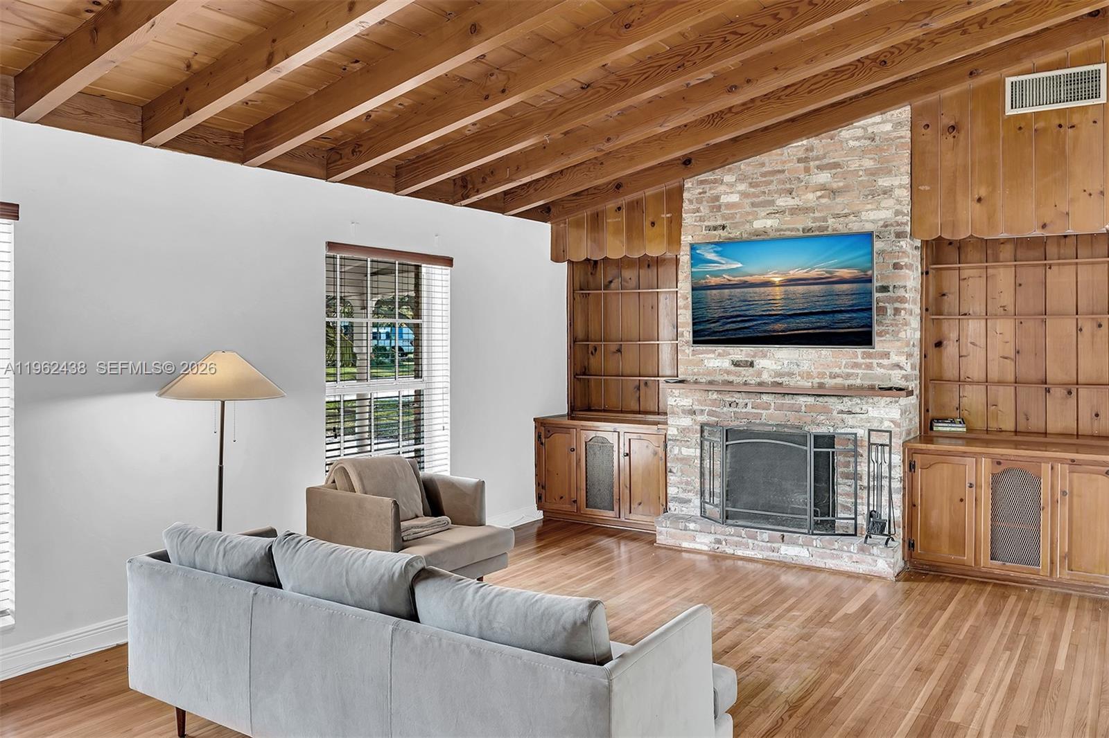 A living room features a brick fireplace, built-in wooden shelving, and a vaulted wood-beam ceiling — 3437 Buchanan St, Hollywood FL 33021, HOLLYWOOD, FL