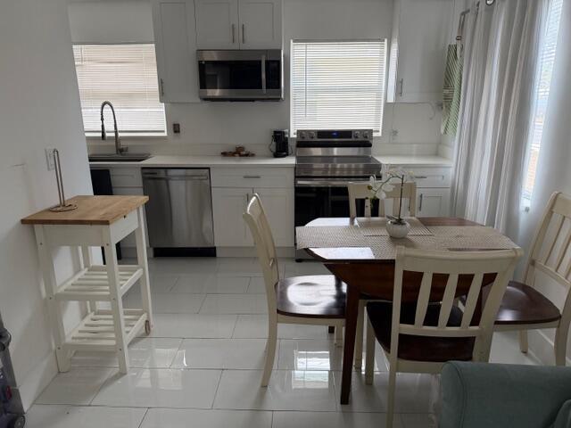 A kitchen with white cabinets, stainless steel appliances, and a small dining table with chairs — 1015 S K Street, FL 33460, FL