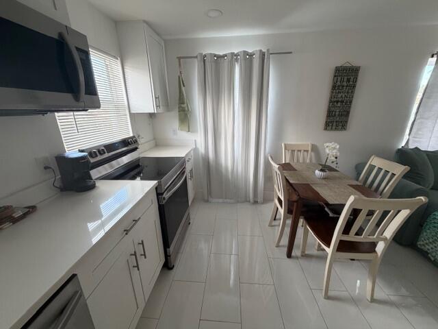 A kitchen with white cabinets and countertops flows into a dining area with tile floors — 1015 S K Street, FL 33460, FL