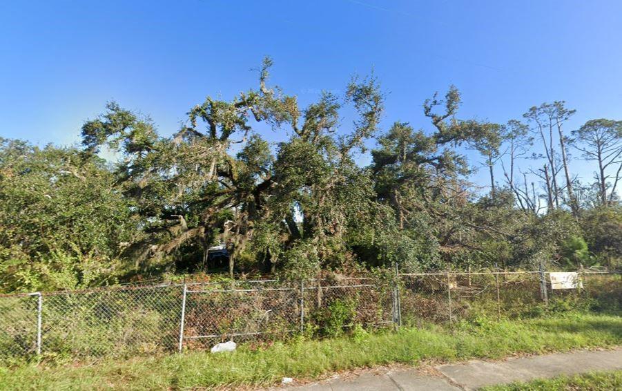 A chain-link fence encloses a wooded lot filled with large, moss-covered oak trees — 400 W ASH STREET, PERRY, FL