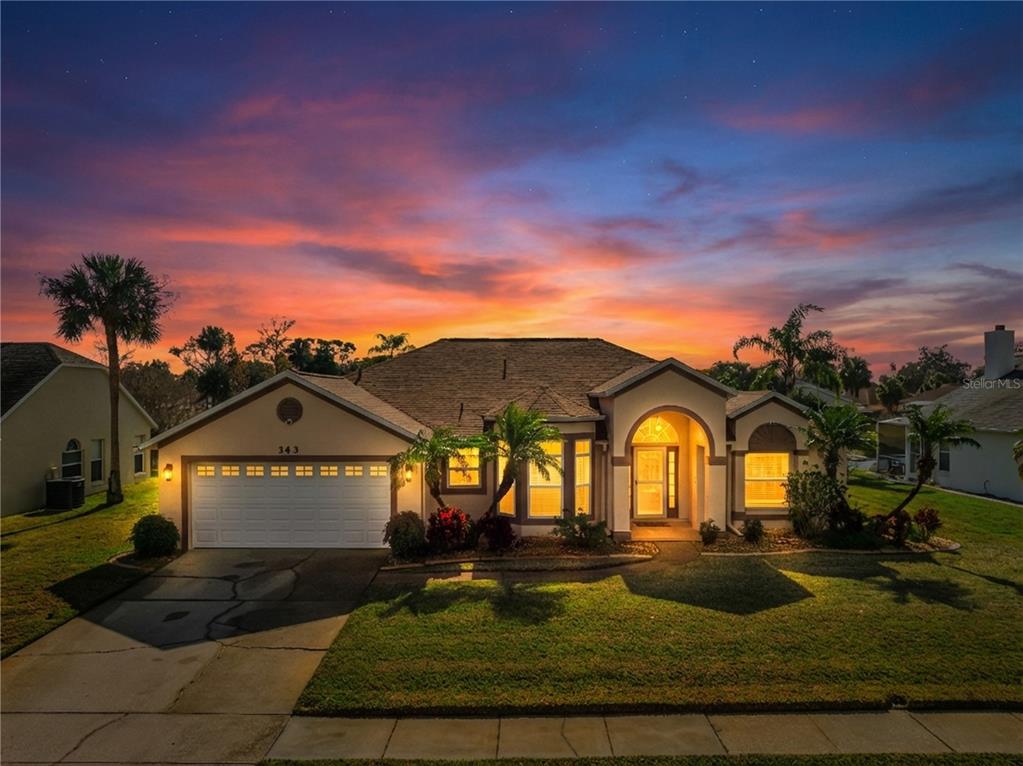 A single-story house with a two-car garage and palm trees at sunset — 343 ALEATHA DRIVE, DAYTONA BEACH, FL