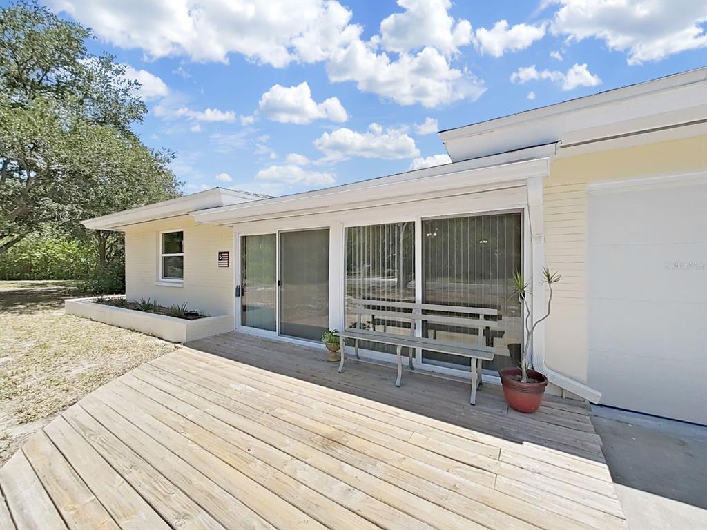 A wooden deck sits in front of a house with sliding glass doors and siding — 5 N KEYSTONE DRIVE, CLEARWATER, FL