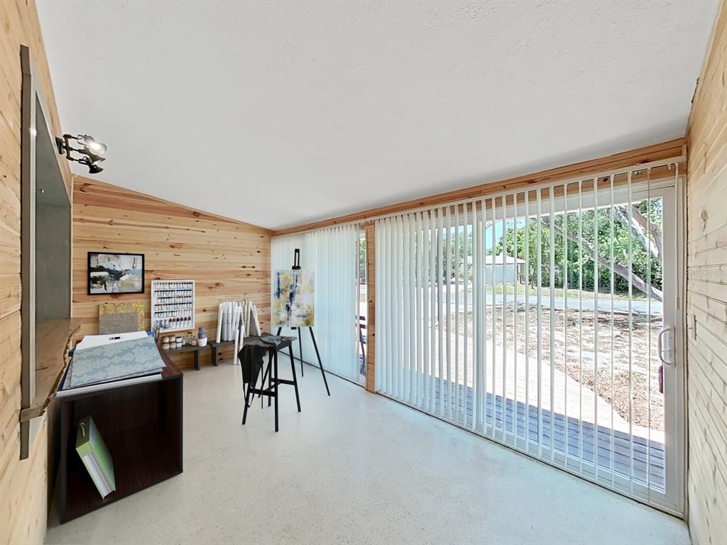 An art studio with wood-paneled walls, a concrete floor, and large sliding glass doors — 5 N KEYSTONE DRIVE, CLEARWATER, FL
