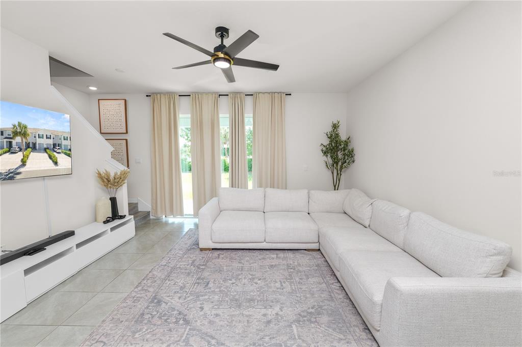 A living room features a large white sectional sofa, a patterned area rug, and a television — 3830 SUNFLOWER FIELD PLACE, PLANT CITY, FL