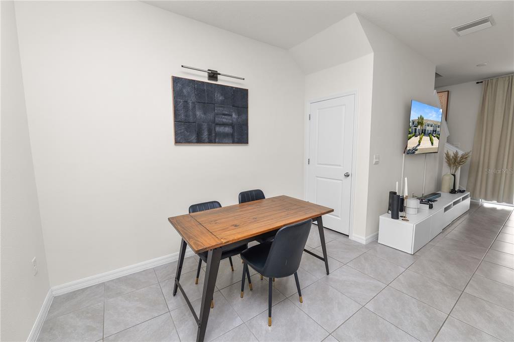 A dining area features a wooden table with black chairs, tile flooring, and wall art — 3830 SUNFLOWER FIELD PLACE, PLANT CITY, FL