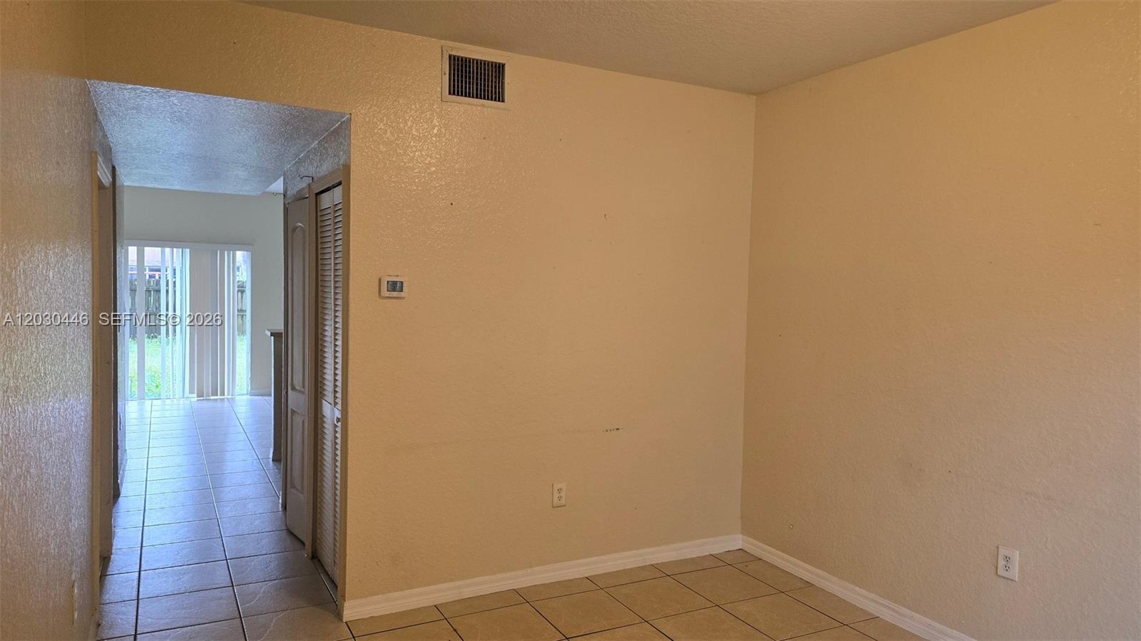 A room with beige walls and tiled flooring features a doorway leading to a patio — 671 SW 10th St, Florida City FL 33034, FLORIDA CITY, FL