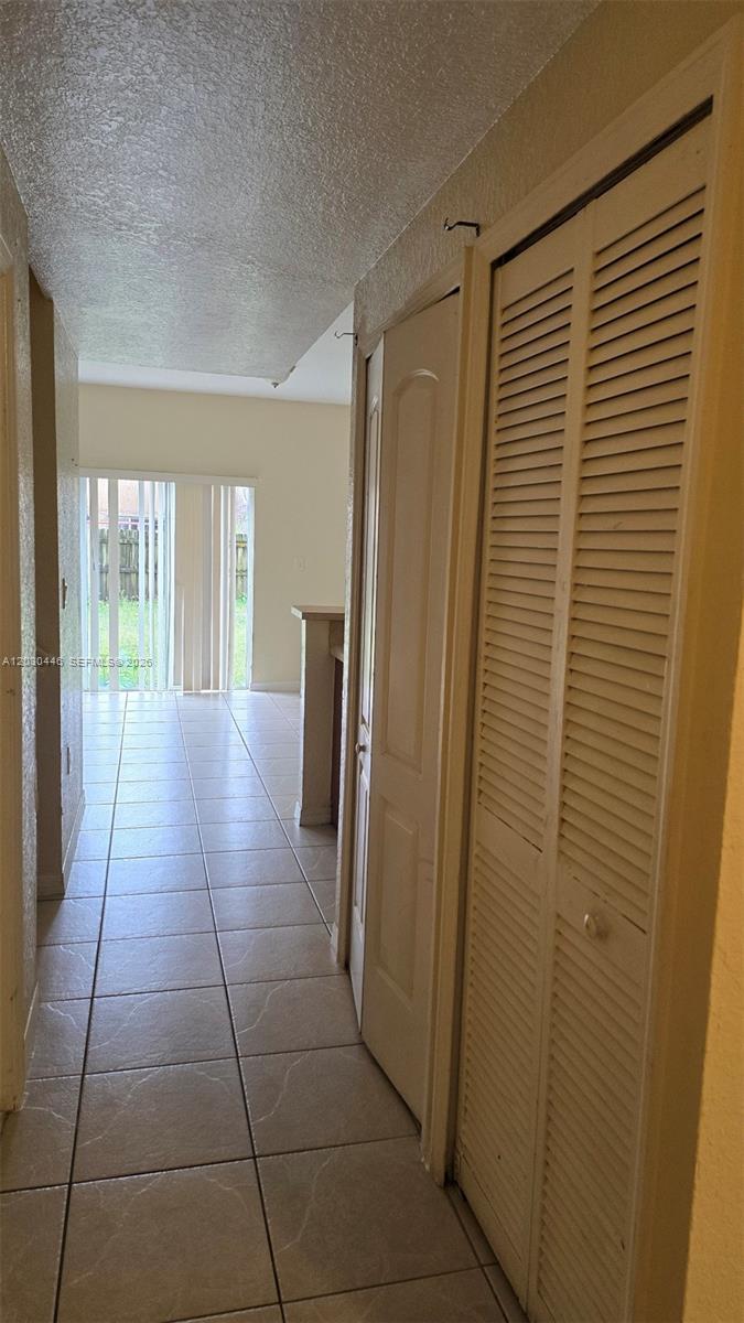 A hallway with tiled floors leads toward a living area with sliding glass doors — 671 SW 10th St, Florida City FL 33034, FLORIDA CITY, FL