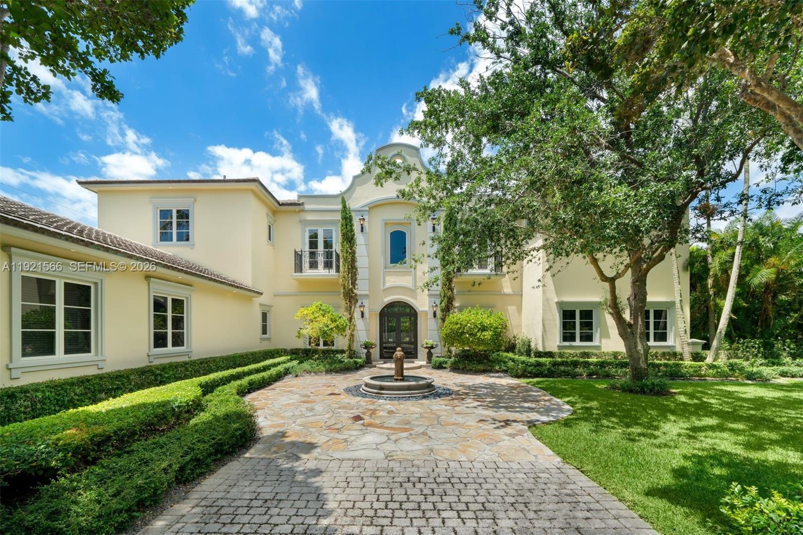 A two-story yellow stucco house features a stone courtyard with a central fountain — 8010 Ponce De Leon Rd, Miami FL 33143, MIAMI, FL