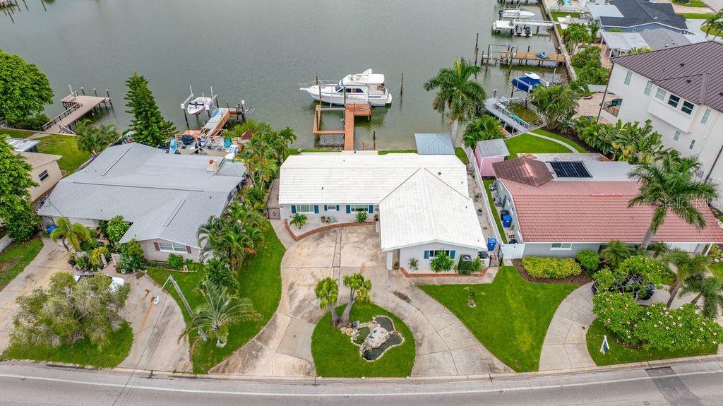 An aerial view shows three waterfront houses with docks, boats, and landscaped yards along a canal — 530 79TH STREET S, ST PETERSBURG, FL