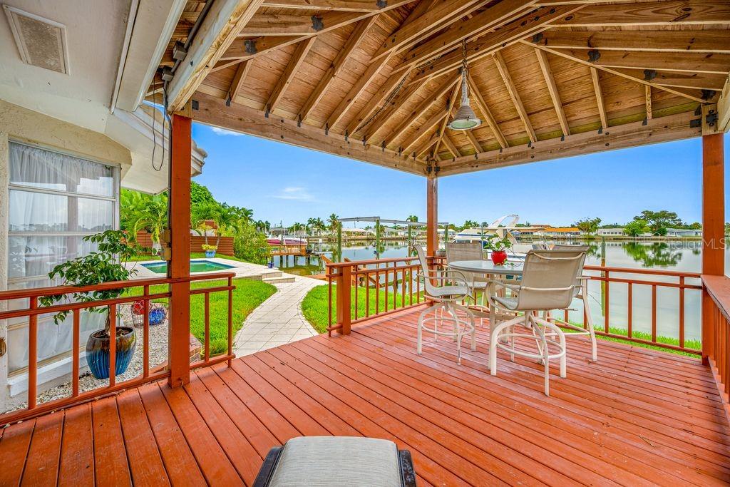 A wooden deck with a covered gazebo overlooks a swimming pool and a canal — 530 79TH STREET S, ST PETERSBURG, FL