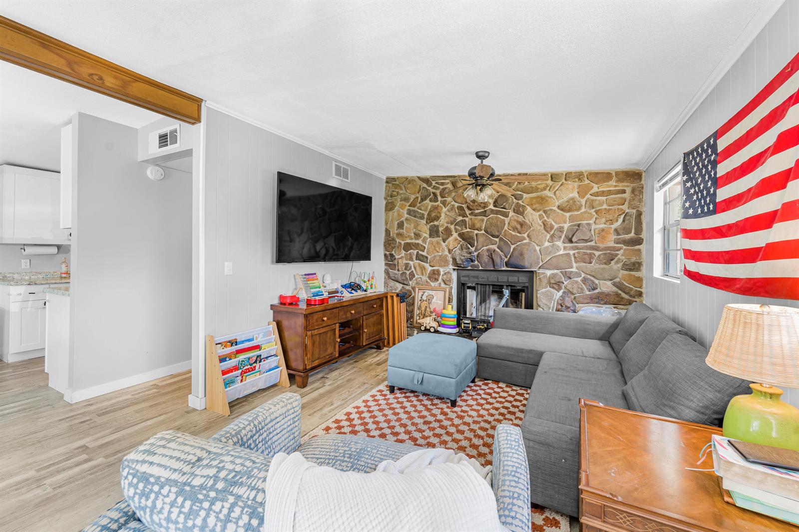 A living room features a stone fireplace, gray sectional sofa, and a large wall-mounted television — 3105 Loretto Road, Jacksonville FL 32223, JACKSONVILLE, FL