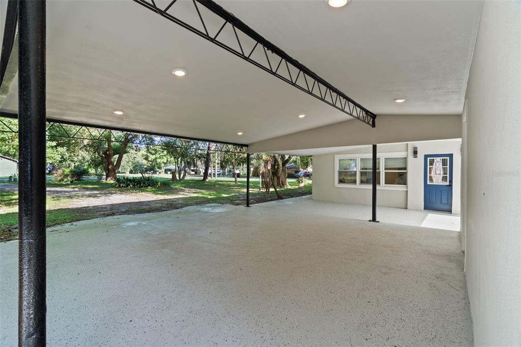 A covered carport with a concrete floor, recessed lighting, and a blue exterior door — 929 ADRIAN COURT, LAKELAND, FL